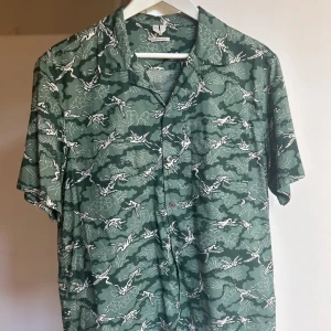 Mönstrad skjorta från Arket - Snygg grön kortärmad skjorta med ”bowlingkrage”. Köpt på Arket för ett par år sedan men har knappt använt den. Därmed sparsamt använd. Väldigt skönt material och är klockren nu på sommaren! Storlek 50 motsvarar en M enligt Arkets storleksguide