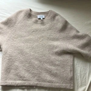 Beige stickad tröja & Other Stories - Supermjuk och fluffig beige stickad tröja från & Other Stories. Modellen har korta ärmar, rund halsringning och en avslappnad passform. Skick 9/10