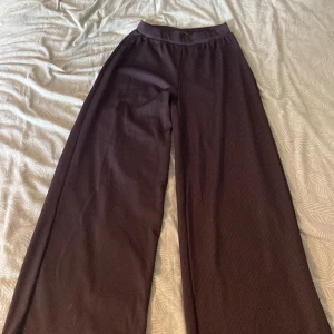 Svarta vida byxor  - Säljer ett par svarta byxor med breda ben och ribbad struktur. De har en bekväm resår i midjan. Perfekta för en chill och avslappnad stil.