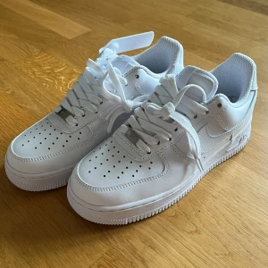 Nike Air Force 1 strl 38 - Säljer dessa klassiska Nike Air Force 1 i helvitt skinn med perforerad tå och platt sula. Snygg och tidlös modell med snörning och diskret Nike-logga på sidan och hälen. Aldrig använda på grund av fel storlek, nyskick med lappar och kartong!🤩Nypris runt 1 249kr