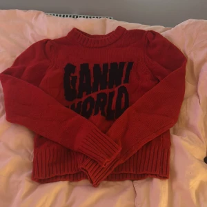 Röd stickad Ganni-tröja XS - Röd stickad tröja från Ganni med svart text 'GANNI WORLD' framtill. Tröjan har ribbade muddar vid hals, ärmslut och nederkant samt lång ärm. Perfekt statement-piece för dig som vill sticka ut med färg och cool logga.