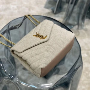 Beige quiltad axelväska från YSL - Säljer en snygg beige quiltad axelväska från YSL med guldiga kedjor och ikonisk logga framtill. Väskan är i textil med detaljer i skinn och har en stilren, mjuk form. Perfekt för dig som vill ha en lyxig och trendig accessoar.