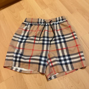 Burberry shorts - Snygga shorts från Burberry med klassiskt rutigt mönster i beige, svart, vitt och rött. Storlek m/L perfekt inför sommaren.