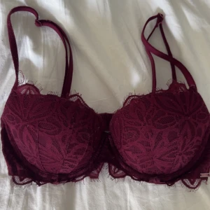 Victorias secret Bh - Säljer en vinröd Pushup bh från Victorias secret med vacker spets och blommigt mönster. Den är rätt så använd därför lite dålig bild på lappen, men den sitter ändå jätte bra och har inga defekter eller så❣️
