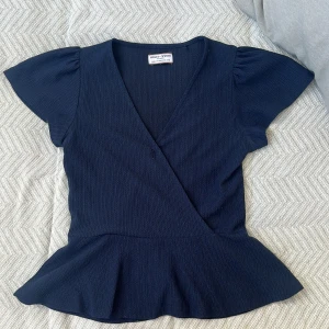 Mörkblå omlottopp  - Supersnygg mörkblå omlottopp från Holly & White med v-ringning och volang nertill. 