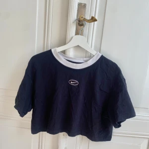 Svart croppad Nike t-shirt - Svart croppad t-shirt från Nike med vit rund halsringning och broderad vit logga på bröstet. Hör av dig om du har några frågor:) 