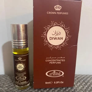 Diwan parfymolja från Al-Rehab - En koncentrerad parfymolja från Al-Rehab, Diwan, i en smidig 6 ml glasflaska med silverfärgad skruvkork. Förpackningen är mörkbrun med guldiga detaljer och arabiska inskriptioner. Oljan har en gyllengul färg och ger en exklusiv känsla.