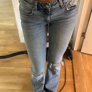 Bootcut jeans från 157 i ljusblå denim - Säljer ett par ljusblå bootcut jeans från 157 i storlek XS. Jeansen har slitna detaljer vid knäna och klassisk femficksdesign. De är i full längd och har dragkedja och knapp framtill. Perfekta för dig som gillar en avslappnad och trendig look.(jag har klippt upp vid midjan som man ser i bild 4 sedan har jag trätt igenom ett snöre så man ska kunna spännamidjan)knappt andvända💕
