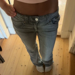 Grå bootcut low jeans - Jättesnygga low waist jeans i ljusgrå! Strl 170 och har lite slitningar längst ner på baksidan vid foten men ingest som syns. Säljs för att de inte används längre och är lite stora. Men jättesköna o snygga jeans❣️