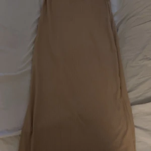 Beige ribbad långkjol från SHEIN - Säljer en beige ribbad långkjol från SHEIN i storlek S. Kjolen är tillverkad i ett mjukt, stretchigt material som sitter bra runt midjan. Säljer pågrund av att den inte passar mig längre. Mycket fin på sommaren till ett vitt linne! 