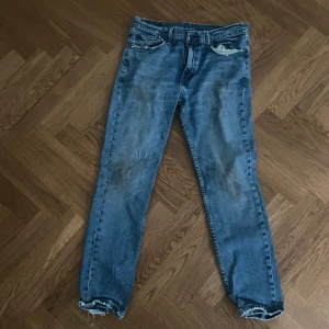 Levi's 501 ljusblå jeans straight fit - Klassiska Levi's 501 jeans i ljusblå tvätt med raka ben och normal passform. Jeansen har fem fickor, knappgylf och slitna detaljer vid benslut och fickor. Perfekta för en avslappnad och tidlös look. Tyvärr är lappen som ska sitta där bak sönder och har gått av! Frakt betalar köparen… Storlek: W35 L32