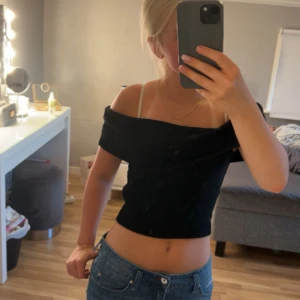 Svart offshoulder topp Gina Tricot - Snygg svart croppad topp från Gina Tricot med offshoulder-design. Toppen är tight och har en stilren look som passar perfekt till jeans eller kjol. Gjord i mjukt bomullsmaterial som känns skönt mot huden.