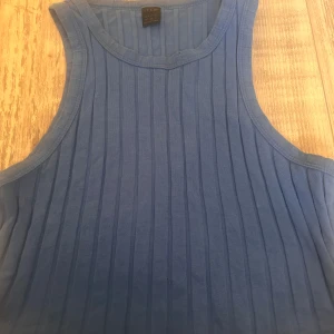 Blå ribbad linnetopp från SHEIN - Säljer en blå ribbad linnetopp från SHEIN. Toppen är ärmlös med rund halsringning och har en tight passform. Perfekt för varma dagar eller som lager under en skjorta. Enkel och stilren design som är lätt att matcha.