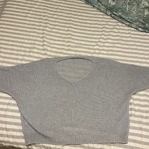 Grå stickad tröja - Säljer en stilren grå stickad tröja med v-ringning. Perfekt för kyligare dagar med sin mjuka och bekväma passform. Tröjan har långa ärmar och en enkel design som passar till det mesta. Ett måste i garderoben för den som gillar klassiska plagg. Kort ärmad