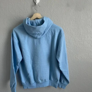 Ljusblå hoodie med spindelnätsdesign - Säljer en cool ljusblå hoodie med en unik spindelnätsdesign på framsidan. Perfekt för en avslappnad stil. Hoodien har en klassisk passform med långa ärmar och en bekväm huva Storlek S men passar också M.