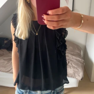 Svart volang blus  - Supersöt blus med volanger 🌟Stolek S men skulle säga att den även passar större & mindre!! Köptes i Spanien för ca 500 kr 💕💕