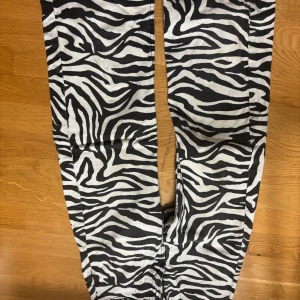 Zebramönstrade jeans, bilderna e upp och ner - Snygga zebramönstrade byxor i svart och vitt. Perfekta för att sticka ut med ett djärvt mönster. Byxorna har en rak passform och är tillverkade i ett bekvämt material.