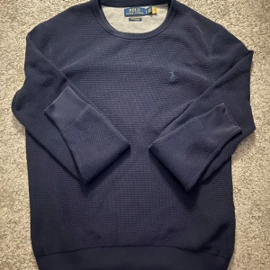Mörkblå tröja från Polo Ralph Lauren - Säljer en stilren mörkblå tröja från Polo Ralph Lauren. Tröjan har en klassisk rund hals och långa ärmar. Perfekt för en avslappnad men ändå elegant look. 