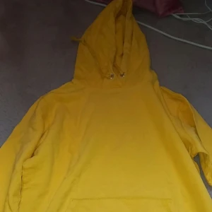 Gul hoodie - Säljer en solgul hoodie med justerbar huva och känguruficka framtill. Perfekt för en avslappnad stil och bekväma dagar. Passar bra till jeans eller mjukisbyxor. Både för killar och tjejer.