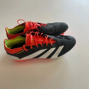 Adidas Predator fotbollsskor - Snygga Adidas Predator fotbollsskor i svart med vita ränder och röda detaljer. Skorna är i mycket bra skick och möjliga defekter syns på bild. Påse och box följer med. Nypris runt 2000
