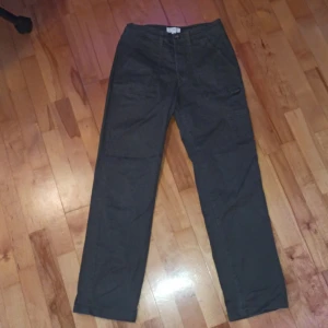 Gröna byxor från H&M - Säljer ett par gröna byxor från H&M. De har en rak passform med hög midja och stängs med knapp och dragkedja. Perfekta för en avslappnad stil.