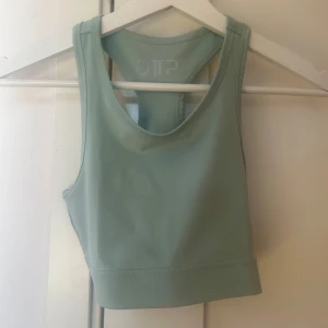 Grön linnetopp från OTP - Snygg och sportig grön linnetopp från OTP med texten 'STRONG' på ryggen. Perfekt för träning med sin bekväma passform och stilrena design. Toppen har en rund halsringning och är ärmlös.