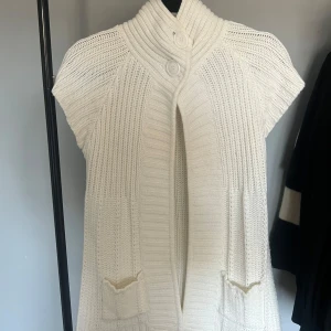 Vit stickad väst med hög krage - Snygg vit stickad väst med hög krage och knappar framtill. Perfekt till våren!💞