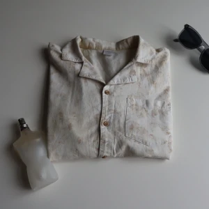  kortärmad linne skjorta - Säljer en beige kortärmad linne skjorta med subtilt mönster. Skjortan har en klassisk krage och knappar framtill samt en bröstficka. Original pris 489 säljer för 239