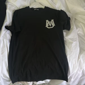 Svart t-shirt från Moncler - Säljer en svart t-shirt från Moncler med ett stort broderat M-logotyp på bröstet och Moncler-märke på ärmen. Perfekt för en stilren look. Självklart äkta, storlek M-L. Skriv vid intresse