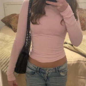 Rosa långärmad topp - Säljer en jättensygg långärmad rosa topp med tight passform. Perfekt för en stilren och enkel look. Storlek xs