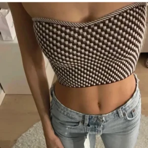 Brun och vit tubtopp mango  - Säljer en snygg brun och vit tubtopp med ett rutigt mönster. Toppen är croppad och perfekt för sommardagar. Passar bra till jeans eller kjol för en avslappnad look.