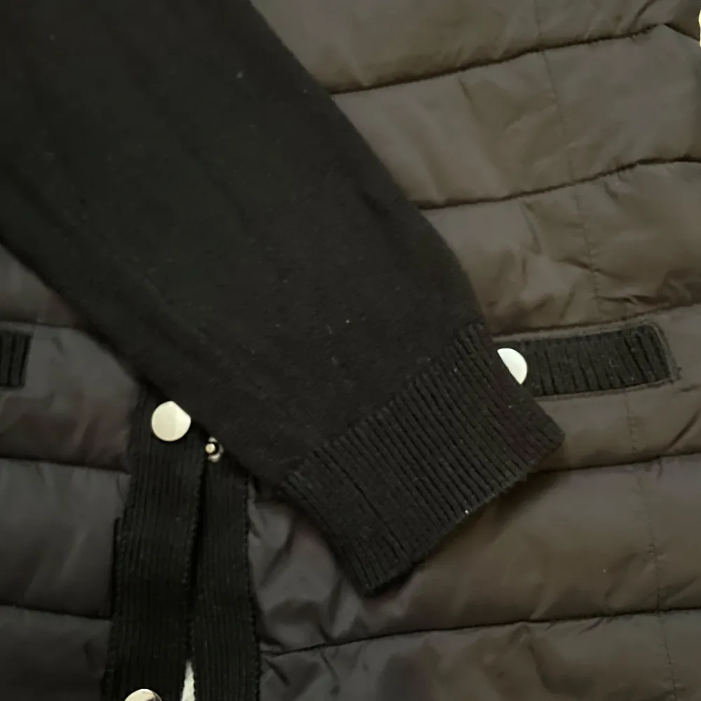 Snygg svart quiltad cardigan jacka med långa ärmar och knappar framtill. Jackan har en stilren design med ribbade detaljer vid ärmslut och nederkant. Perfekt för kyligare dagar. Passar s/m. Takit.