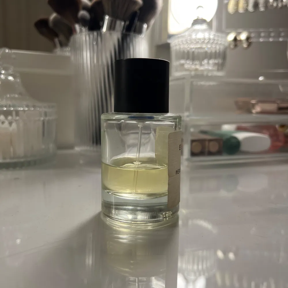 Säljer en elegant flaska av Essnce Perenne Amore Eau de Parfum. Flaskan är genomskinlig med en enkel, stilren design och har en svart kork. Doften är subtil och sofistikerad, perfekt för den som söker något unikt.. Perfume.
