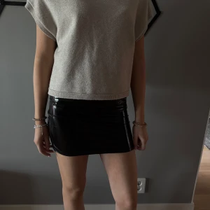 Svart lackkjol i medellängd - Säljer en svart, glansig lackkjol i medellängd. Kjolen har en tight passform och är tillverkad i ett syntetmaterial som ger en cool och modern look. Nyskick och perfekt till sommaren💗