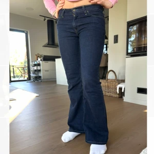 Mörkblå Lågmidjade bootcut jeans från Levi's - Säljer ett par mörkblå jeans från Levi's med klassisk bootcut-passform. Jeansen har fem fickor, gylf med dragkedja och knäppning samt tydliga sömmar baktill. Perfekta för dig som gillar en tidlös jeanslook. Längden är original 34 men har sytt upp dom så de passar snare 32 
