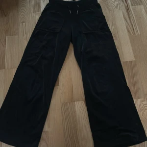 Svarta vida byxor från 157 - Säljer ett par svarta vida byxor från 157 med resår och snörning i midjan. Byxorna har stora fickor framtill och är tillverkade i ett mjukt material som känns skönt mot huden. Perfekta för en avslappnad stil. Använd ganska många gånger men bra skick