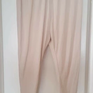 Beiga lösa haremsbyxor  - Snygga beiga byxor med loose fit och avslappnad passform. Perfekta för en chill stil och enkla att matcha med olika toppar. Byxorna har hög midja och är tillverkade i ett mjukt material som känns skönt mot huden.