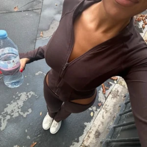 Brun zip hoodie och yoga byxor  - Säljer en brun zip hoodie och byxor från Gina med tight passform och långa ärmar. Tröjan har dragkedja framtill och är tillverkad i ett stretchigt syntetmaterial, perfekt för träning eller en sportig look.