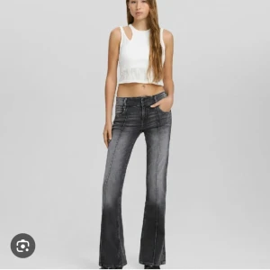 Mörkgrå bootcut jeans  - Snygga svarta bootcut jeans med markerade sömmar från Bershka. Byxorna har låg midja och är storlek S