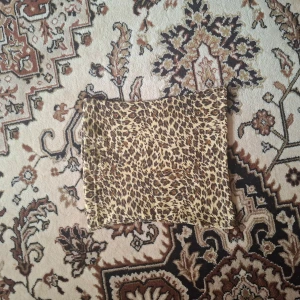 Leopardmönstrad kuvertväska - Säljer en fyrkantig kuvertväska med leopardmönster. Väskan har en enkel design utan synliga detaljer eller logga. Perfekt för dig som vill sticka ut med ett djurmönster.