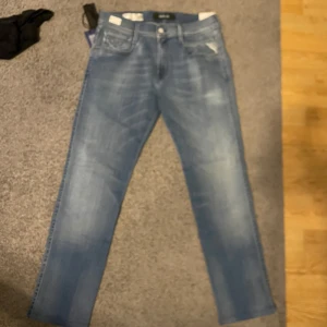 Replay Anbass ljusblå jeans slim fit - Säljer ett par Replay Anbass jeans i ljusblå tvätt med slim fit. Jeansen har klassisk femficksdesign, dragkedjegylf och snygga slitningar framtill. Handgjorda detaljer och etikett på insidan. Perfekta för dig som gillar en smalare passform. Jeansen är helt nya och aldrig använda. De är 30 i midjan och 30 i längden. Jag är 178 och de sitter bra på mig. 