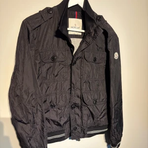 Moncler Jacka - En riktigt snygg field jacket från moncler i modellen ”delonix”. Bra skick förutom att det saknas en knapp, därav pris! Storlek 2 morsvarar runt S-Xs. Hör av er vid frågor!