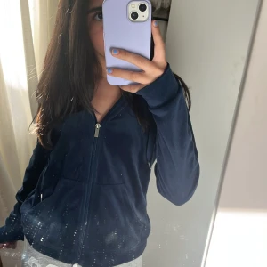 Mörkblå hoodiejacka med dragkedja - Mysig mörkblå hoodiejacka med dragkedja framtill och huva med snören. Jackan har fickor på sidorna och är långärmad. Perfekt för en avslappnad stil.