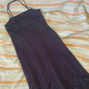 Lila långklänning med tunna axelband från Cope - Säljer en långklänning från Cope med tunna axelband och slätt tyg. Klänningen har en elegant och enkel design med lätt fodrad insida. Perfekt för dig som gillar minimalistisk stil.