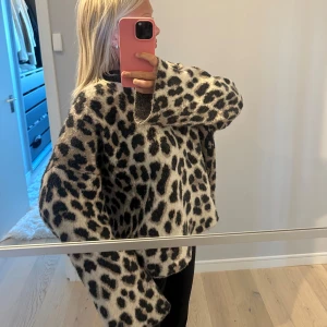 Leopardmönstrad stickad tröja - Säljer en oversized stickad tröja med leopardmönster i svart och beige. Tröjan har långa ärmar och en lös passform, perfekt för att sticka ut i mängden. Supermjuk och skön att bära.