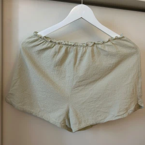 Ljusgröna shorts med resårmidja - Säljer ett par ljusgröna shorts med resår i midjan. De är tillverkade i ett tunt, strukturerat tyg som känns svalt och luftigt. Perfekta för varma dagar. Sparsamt använd.