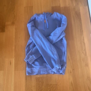 Ljusblå hoodie från Nike - Säljer en ljusblå hoodie från Nike med klassisk huva och dragsko. Tröjan har lång ärm och en broderad Nike-logga framtill. Tillverkad i mjukt bomullsmaterial med Dri-FIT-teknologi för extra komfort.