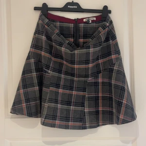 Rutig kjol från Hampton Republic - Säljer en snygg rutig kjol från Hampton Republic i grått, svart, vitt och inslag av rött och orange. Kjolen har dragkedja bak och är i en klassisk A-linjeformad modell. Perfekt för dig som gillar tidlös stil!