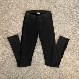 Jeans med glitter detaljer - Säljer ett par svarta skinny jeans med glitterremsa längs sidorna. Byxorna har hög midja och är stretchiga för en bekväm passform. Som man ser på tredje bilden så har jag klippt upp längst ner på benen, och på fjärde bilden ser man en liten spricka på ena bakfickan, så av dessa anledningar så är jag villig att sänka priset lite om man vill det. Skriv om du har frågor o läs gärna min bio innan du köper🫶🏻🫶🏻