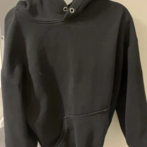 Svart hoodie med ficka - En klassisk svart hoodie med huva och magficka. Perfekt för en avslappnad stil och enkel att matcha med det mesta. Tröjan har långa ärmar och dragsko vid huvan.